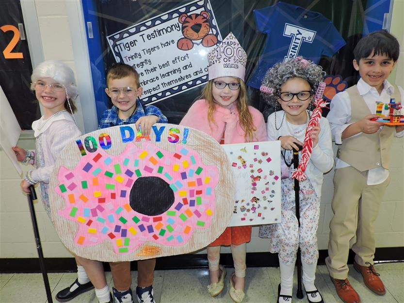 five students dressed as 100 year olds, one is holding a donut